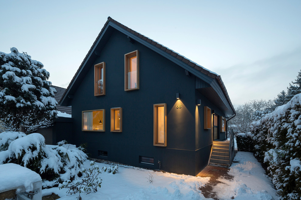 Пример оригинального дизайна: двухэтажный, синий частный загородный дом в скандинавском стиле с облицовкой из цементной штукатурки и черепичной крышей