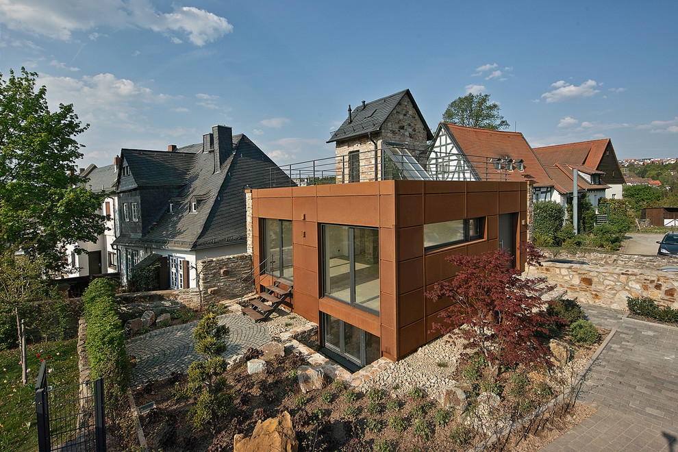 Diseño de fachada marrón actual grande de dos plantas con tejado plano y revestimiento de metal