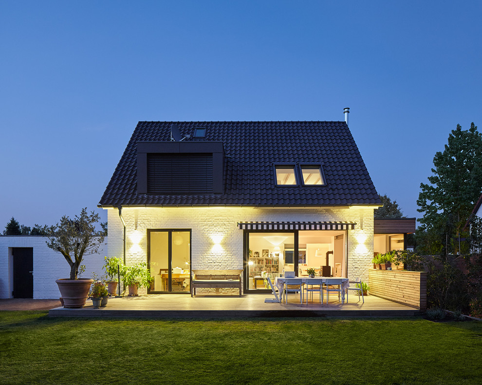 Photo of a medium sized and white mediterranean bungalow brick house exterior in Dusseldorf with a pitched roof.