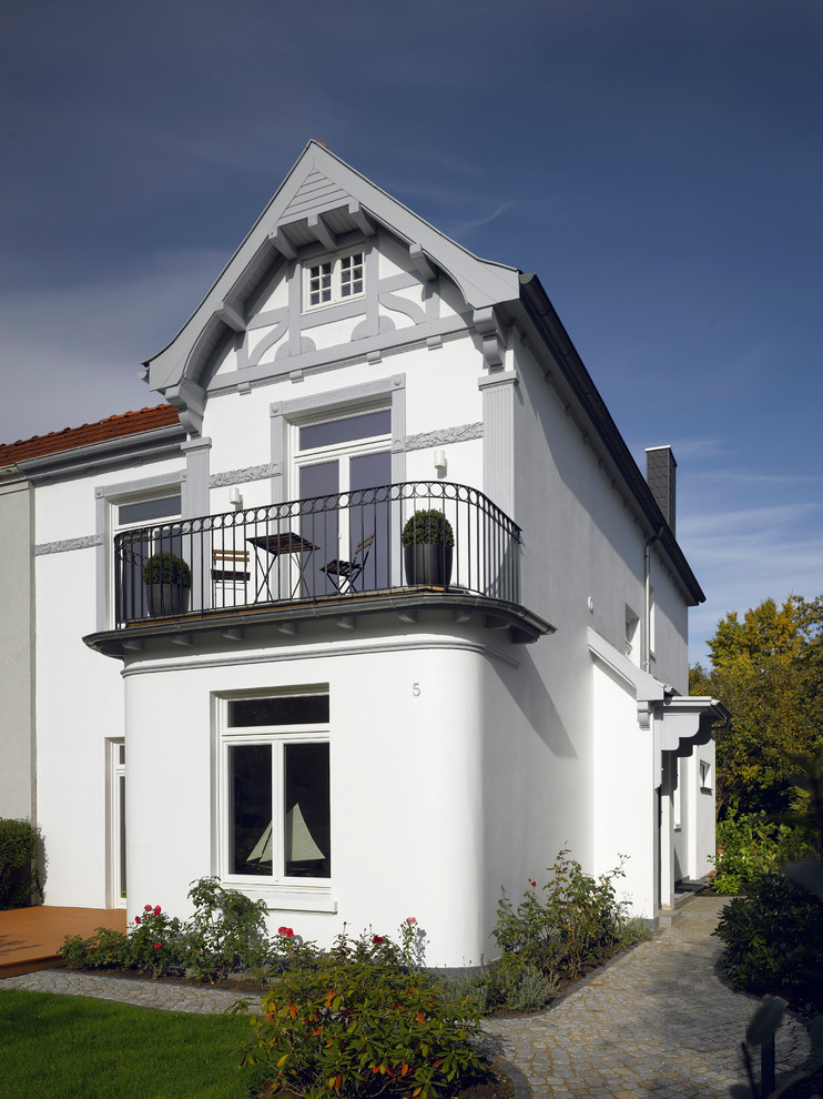 Esempio della facciata di una casa piccola bianca classica a due piani con tetto a mansarda