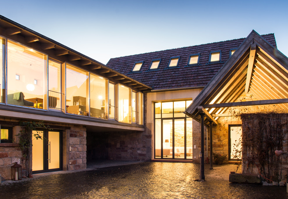 Imagen de fachada de casa marrón de estilo de casa de campo grande de tres plantas con revestimientos combinados, tejado a dos aguas y tejado de teja de barro