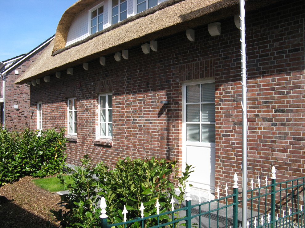 Foto de fachada de piso roja campestre pequeña de dos plantas con revestimiento de ladrillo y tejado a dos aguas