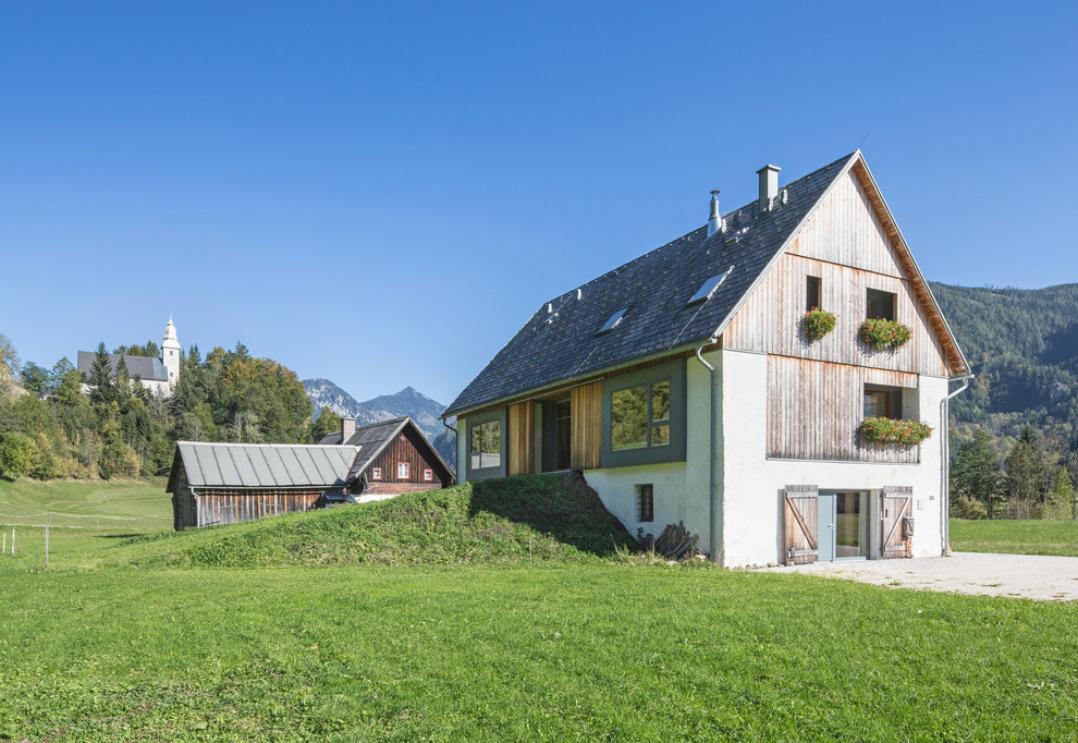 Imagen de fachada de casa beige campestre de tamaño medio de tres plantas con revestimientos combinados, tejado a dos aguas y tejado de teja de madera
