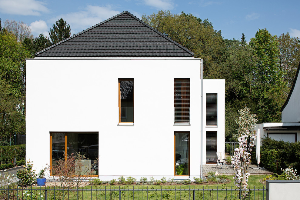 Idées déco pour une façade de maison blanche moderne à un étage avec un toit à quatre pans.