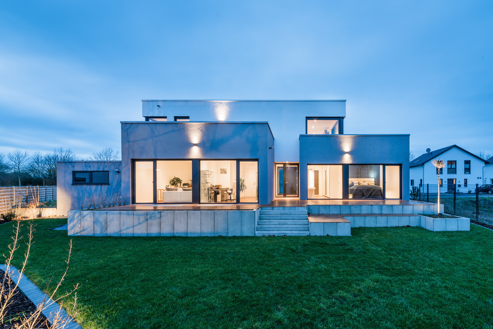 Стильный дизайн: двухэтажный, белый частный загородный дом в современном стиле с облицовкой из цементной штукатурки и плоской крышей - последний тренд