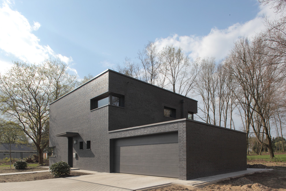 Diseño de fachada negra contemporánea de tamaño medio de dos plantas con tejado plano y revestimiento de ladrillo