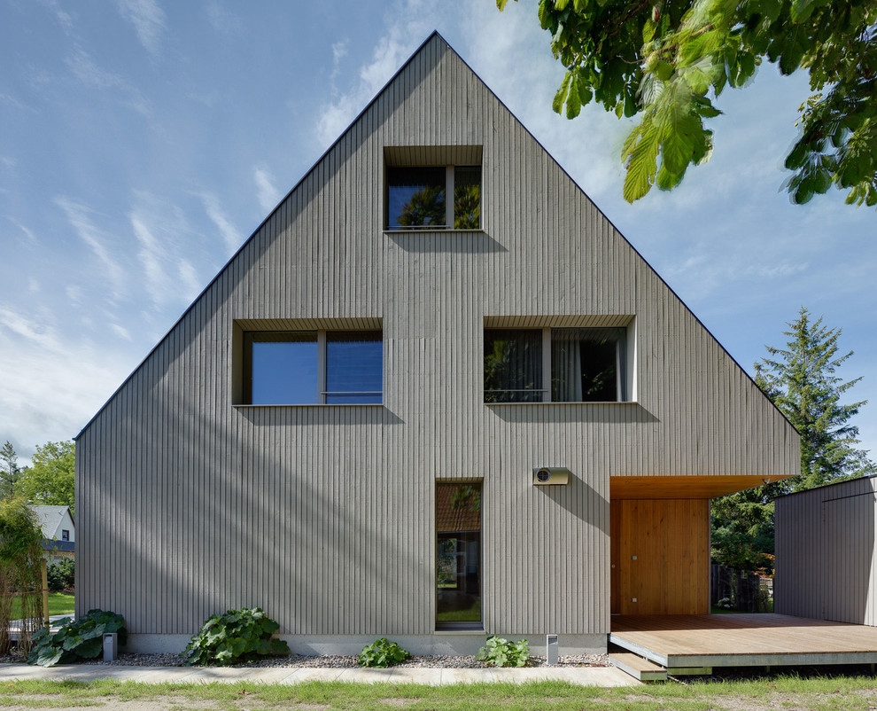 Diseño de fachada gris actual de tamaño medio de tres plantas con revestimiento de madera y tejado a dos aguas