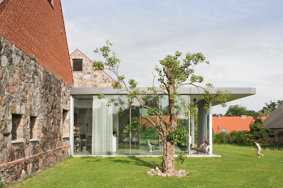 Esempio della facciata di una casa piccola contemporanea con tetto piano e rivestimento in vetro
