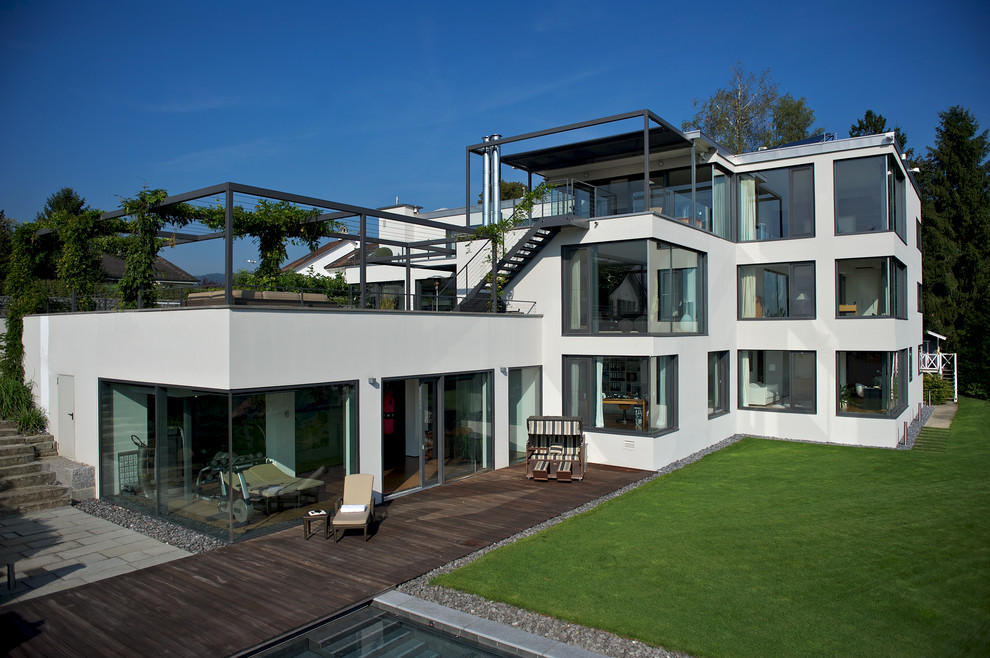 Modelo de fachada de casa blanca contemporánea extra grande de tres plantas con revestimiento de estuco y tejado plano