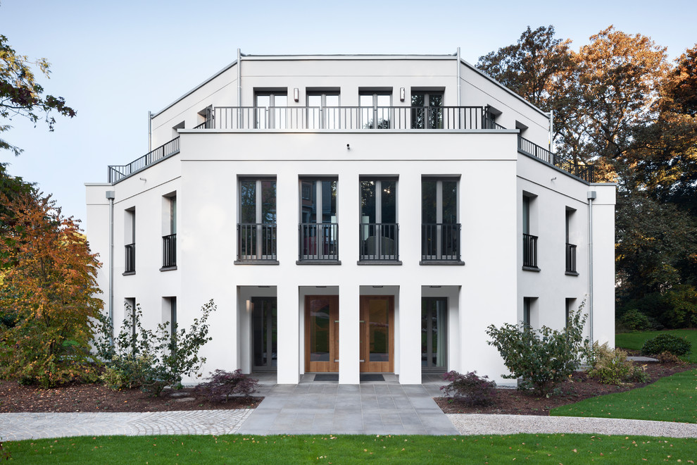 Large and white traditional render detached house in Cologne with three floors and a flat roof.
