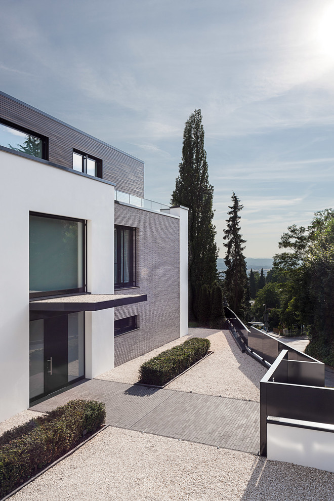 Inspiration for a large and white contemporary house exterior in Cologne with three floors, mixed cladding and a flat roof.
