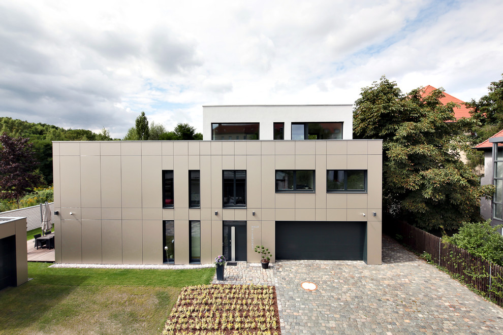 This is an example of a large and beige modern house exterior in Leipzig with three floors and a flat roof.