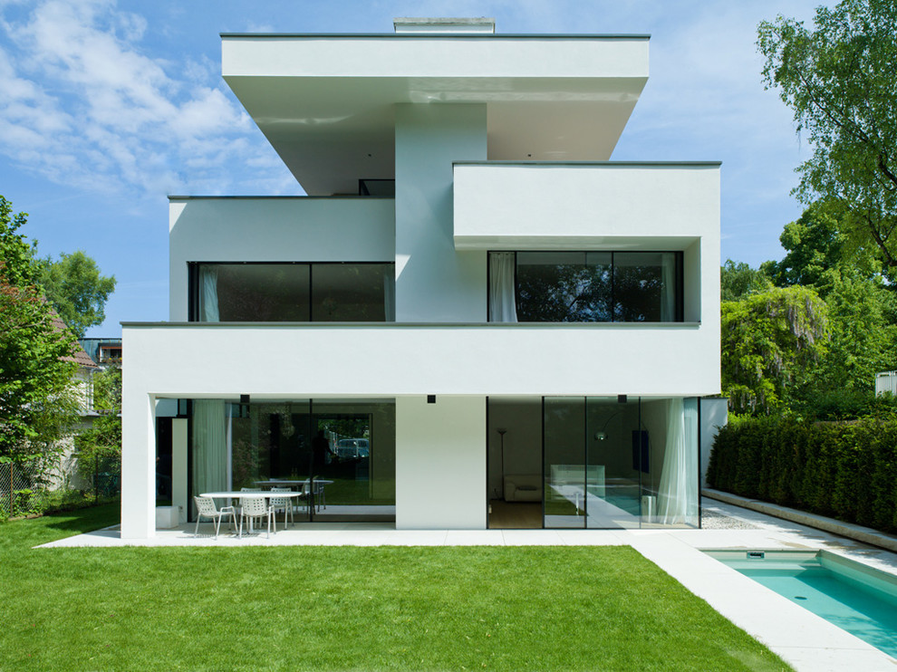 Idées déco pour une façade de maison blanche moderne en stuc à deux étages et plus et de taille moyenne avec un toit plat.