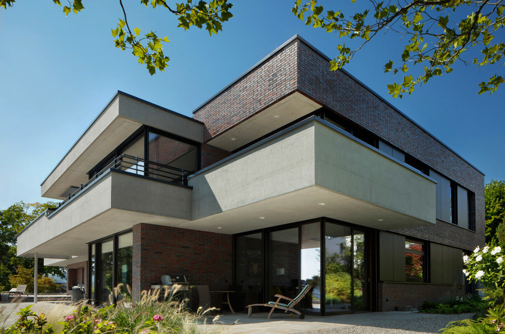 Zweistöckiges Modernes Einfamilienhaus mit Backsteinfassade, roter Fassadenfarbe und Flachdach in Sonstige