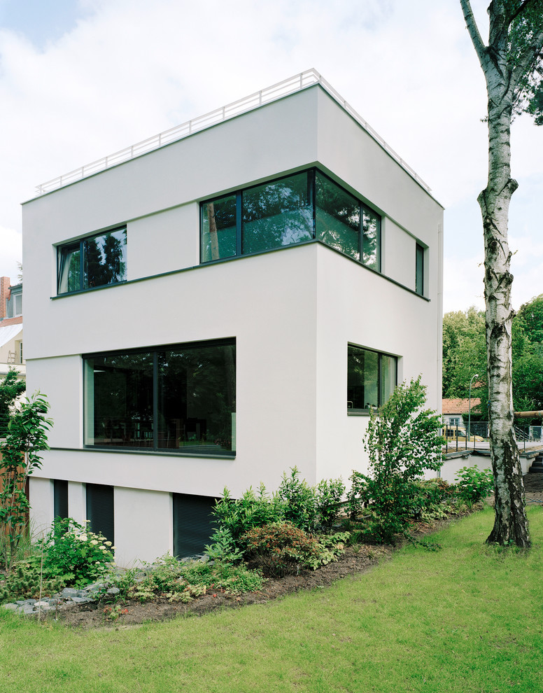 Dreistöckiges, Mittelgroßes Modernes Haus mit Putzfassade, weißer Fassadenfarbe und Flachdach in Berlin
