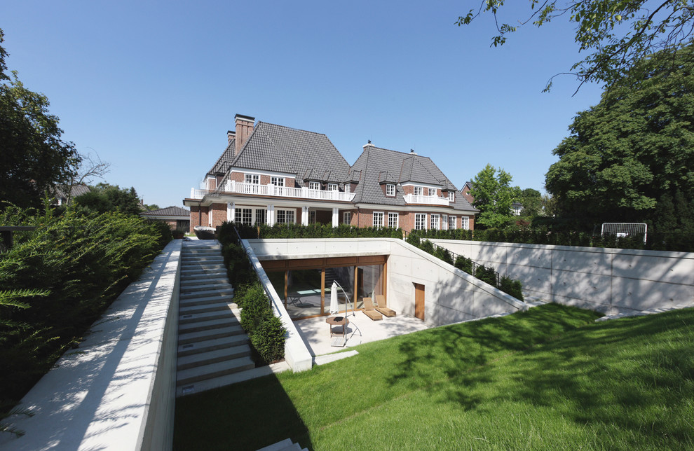 Cette image montre une façade de maison grise design en béton de taille moyenne et à deux étages et plus avec un toit à quatre pans.