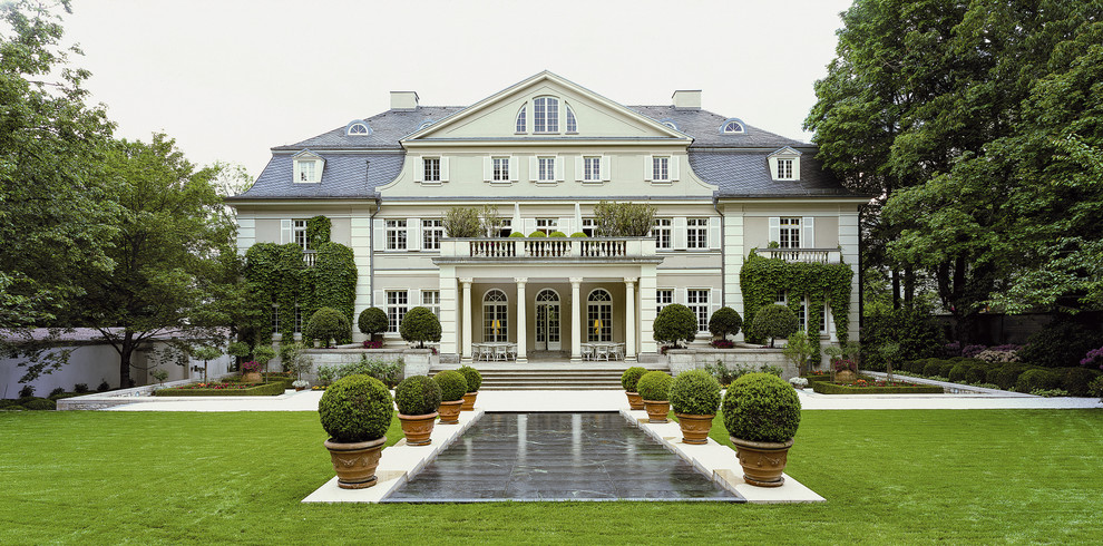 Diseño de fachada beige tradicional grande de tres plantas con revestimiento de estuco y tejado a doble faldón