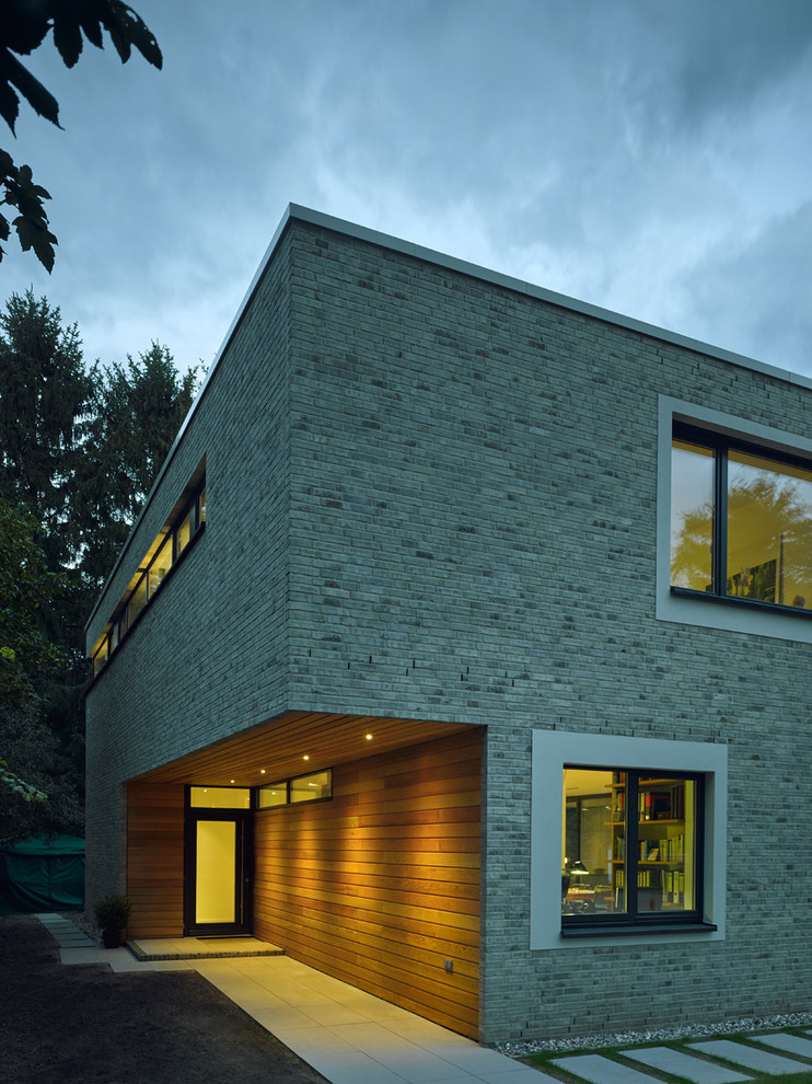 Modern inredning av ett mellanstort beige hus, med tegel, platt tak och två våningar