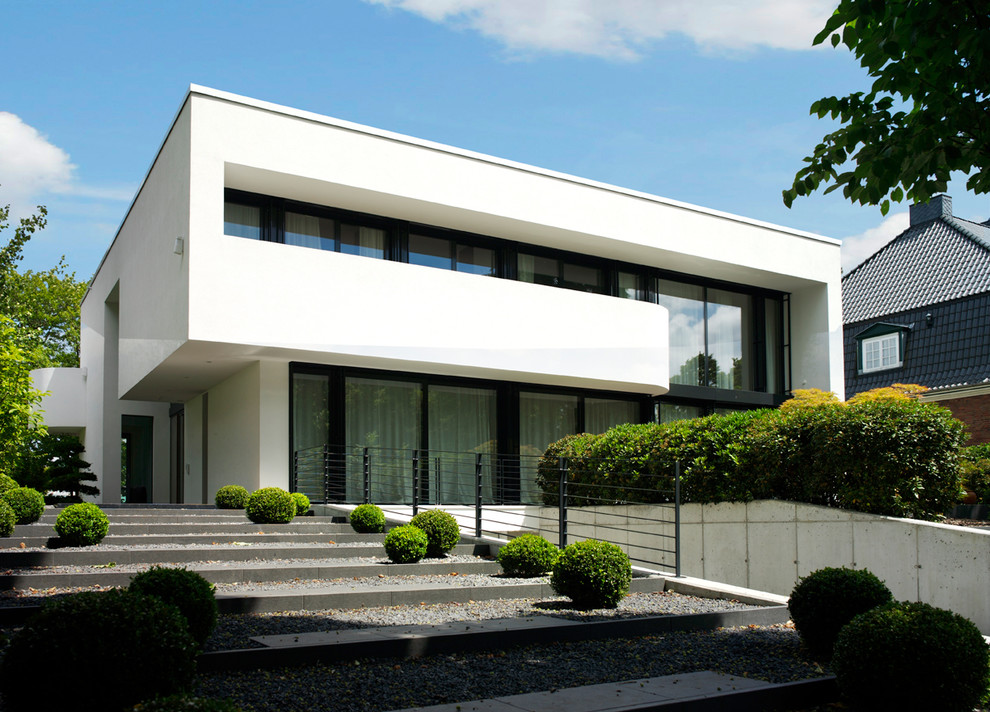 Foto della facciata di una casa ampia bianca contemporanea a due piani con tetto piano e rivestimento in stucco