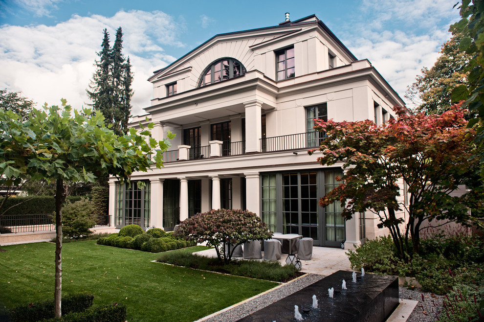 Immagine della facciata di una casa ampia beige classica a tre piani con rivestimento in stucco