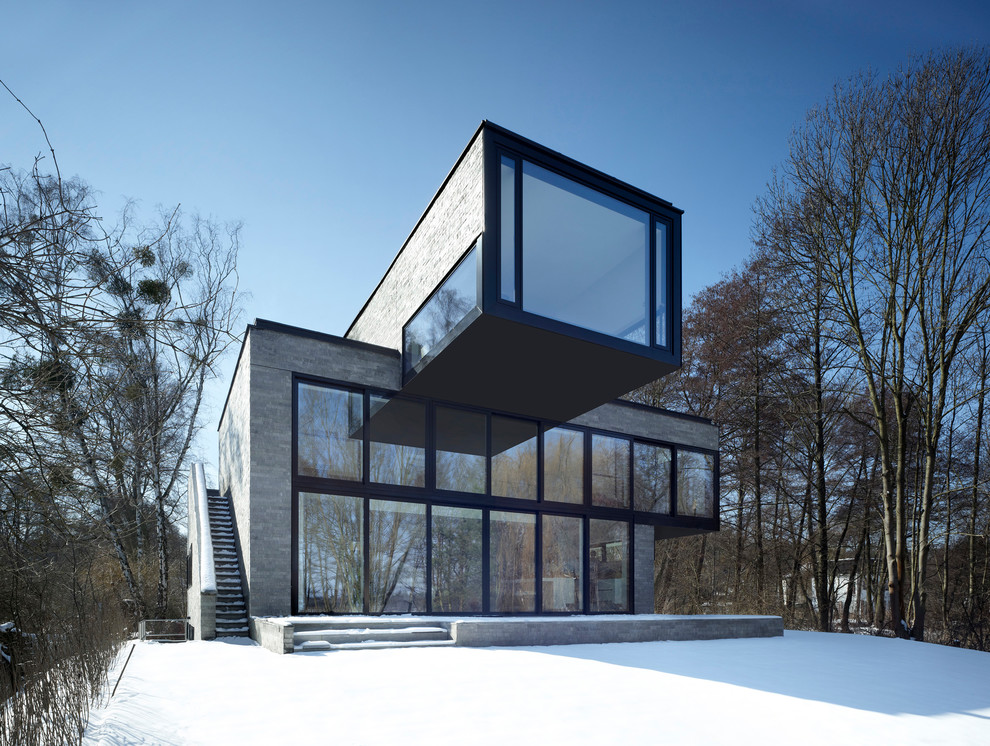 Ispirazione per la facciata di una casa grande grigia contemporanea a tre piani con rivestimento in vetro e tetto piano