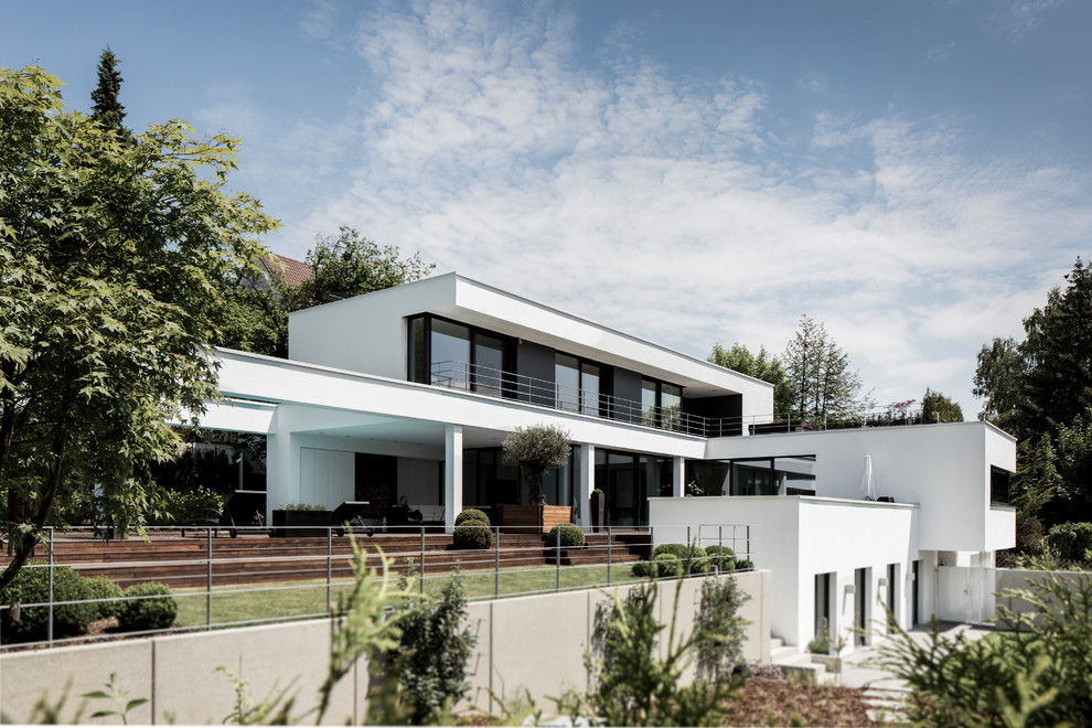 Diseño de fachada de casa blanca minimalista grande de tres plantas con revestimiento de estuco y tejado plano