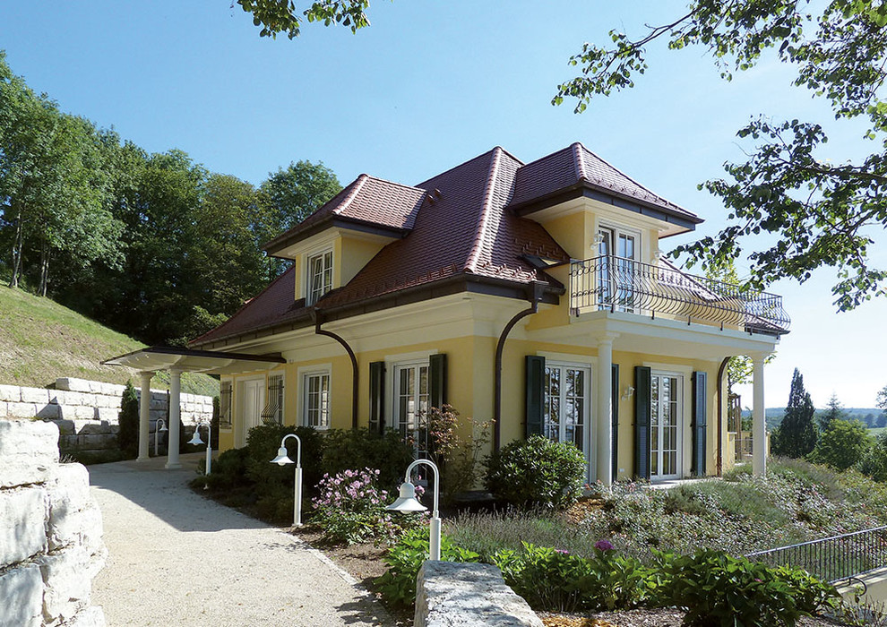 Photo of a yellow traditional two floor render house exterior in Stuttgart with a hip roof.