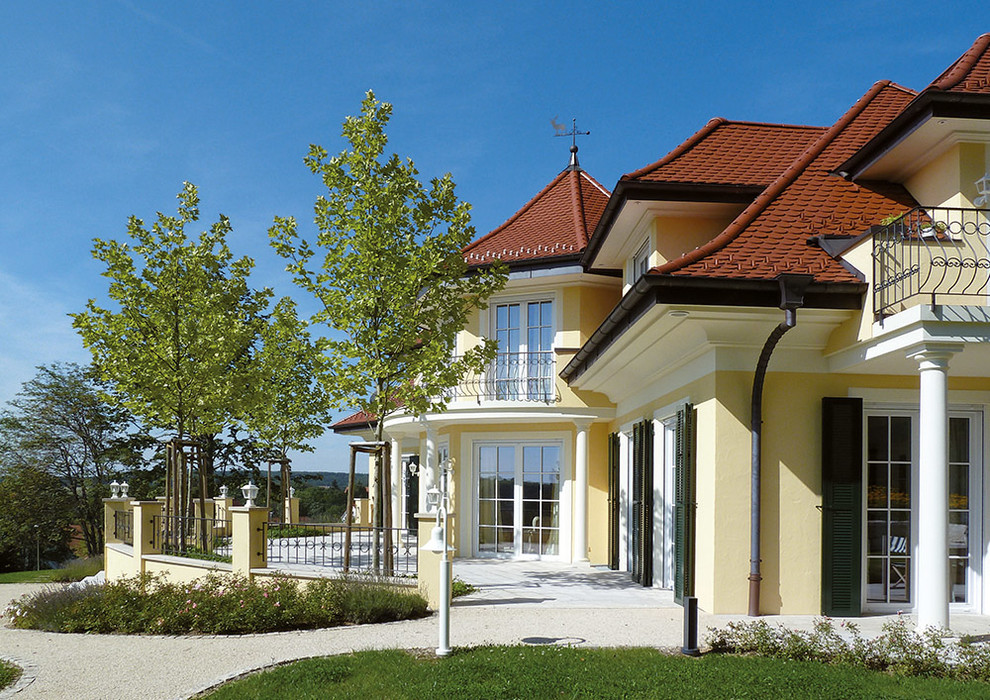 Пример оригинального дизайна: желтый, двухэтажный дом в классическом стиле с облицовкой из цементной штукатурки