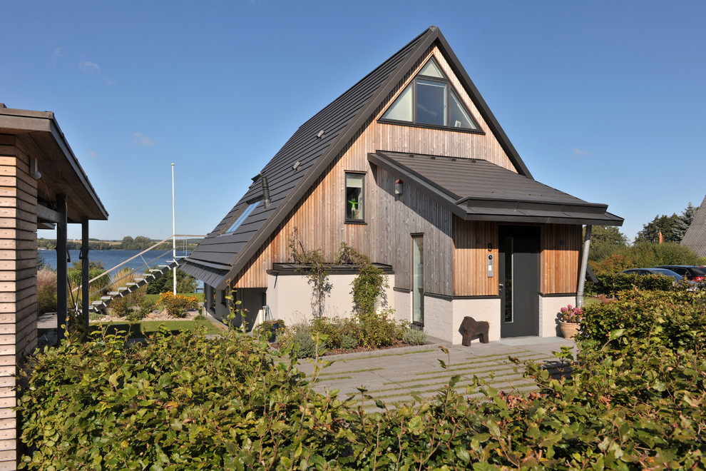 На фото: двухэтажный, деревянный дом среднего размера в современном стиле с двускатной крышей с
