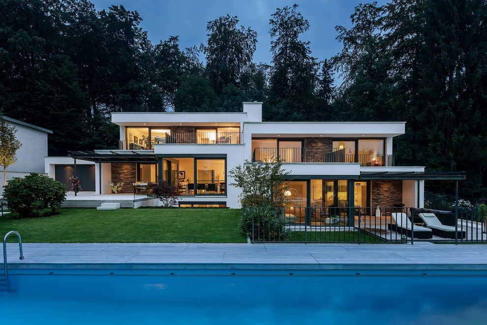 Mittelgroßes Modernes Haus mit weißer Fassadenfarbe und Flachdach in München
