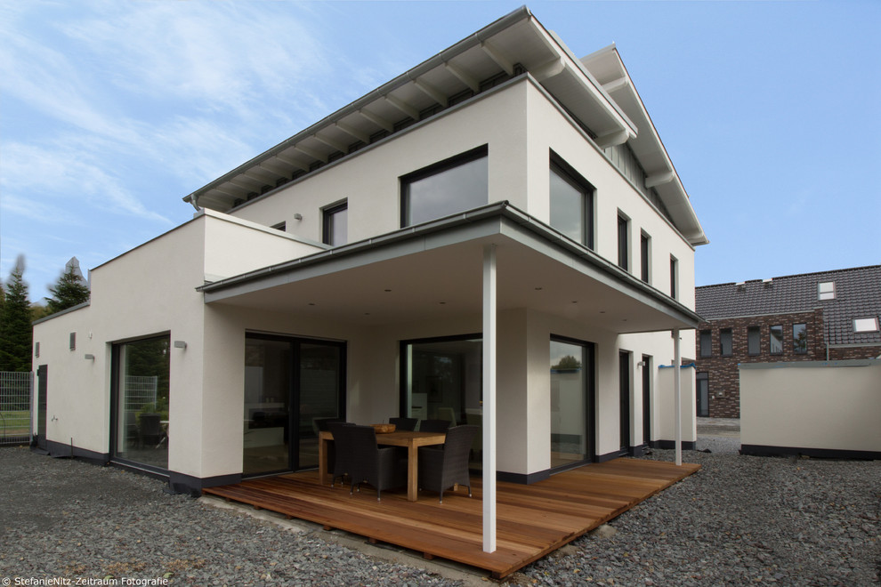 Идея дизайна: двухэтажный, белый частный загородный дом среднего размера в стиле модернизм с облицовкой из цементной штукатурки, односкатной крышей и крышей из смешанных материалов