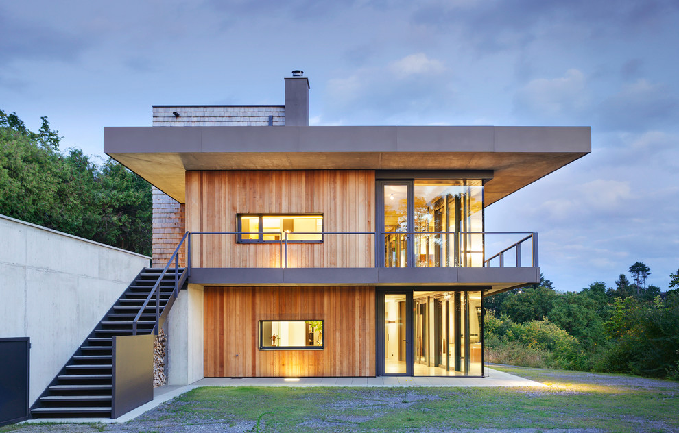 На фото: большой, трехэтажный, деревянный, коричневый частный загородный дом в современном стиле с плоской крышей с