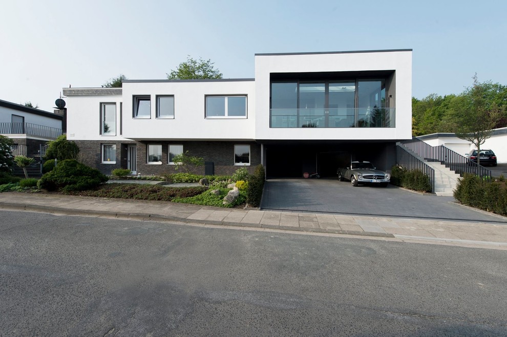 Стильный дизайн: двухэтажный, белый дом в стиле модернизм с плоской крышей и комбинированной облицовкой - последний тренд