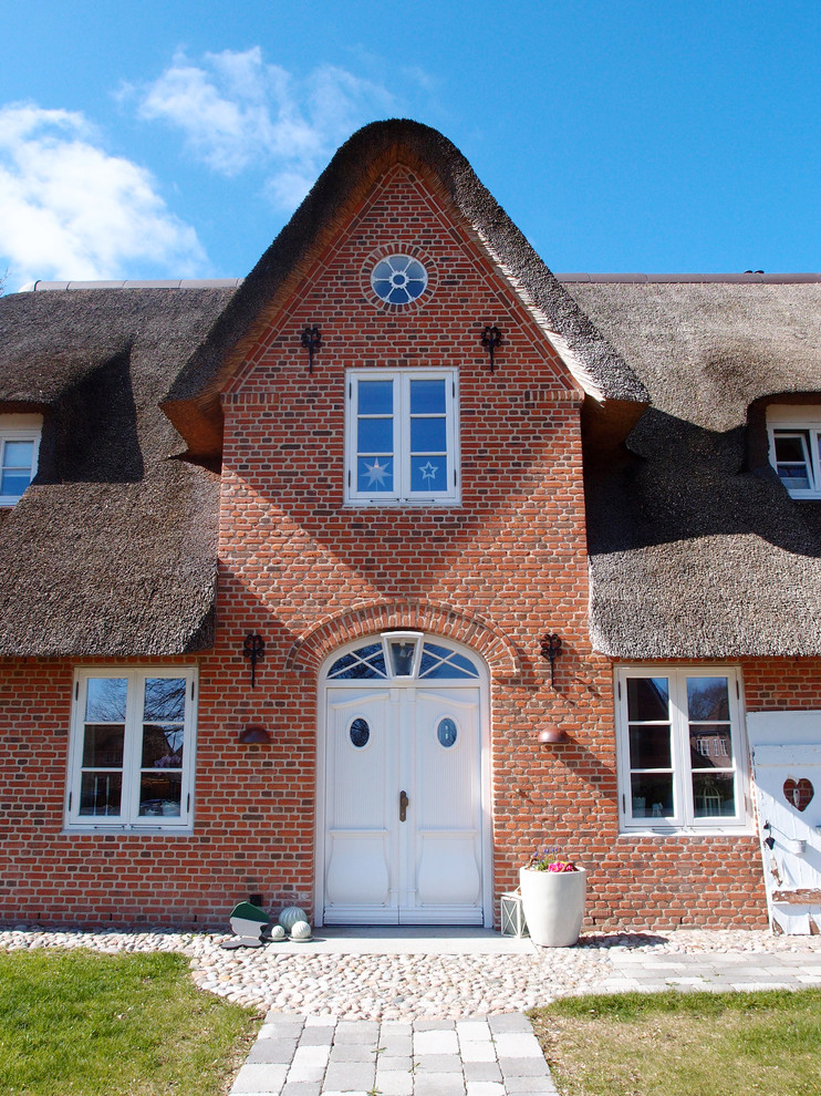 Immagine della facciata di una casa country a due piani con rivestimento in mattoni