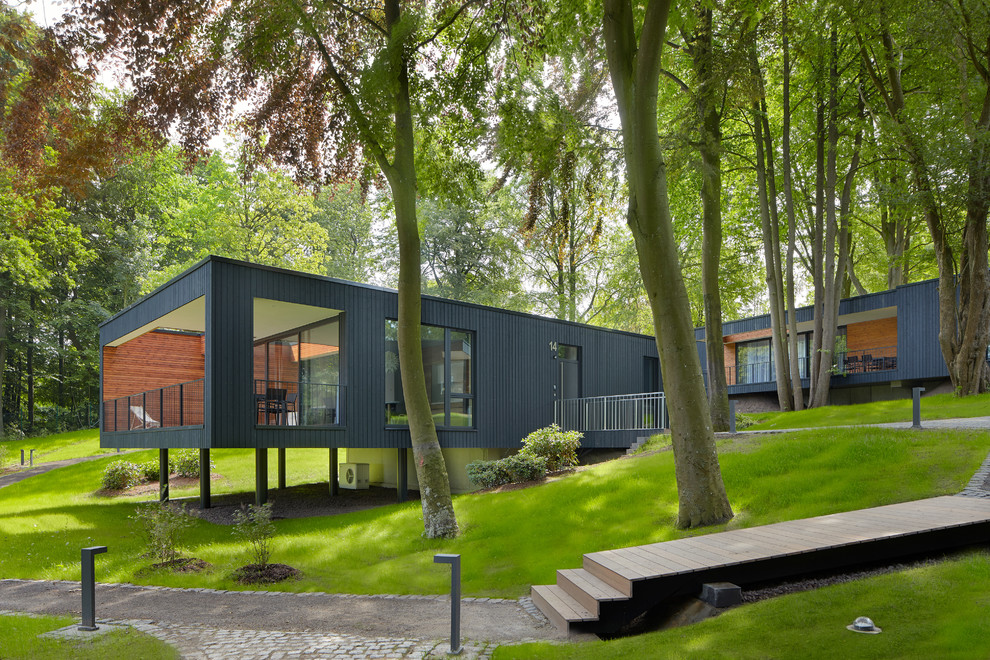 Black and large contemporary bungalow detached house with a flat roof and wood cladding.