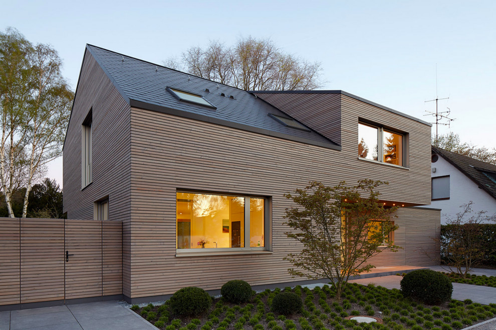 Inspiration for a brown and medium sized contemporary two floor house exterior in Dusseldorf with wood cladding and a pitched roof.