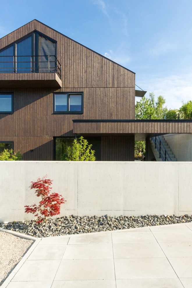 Diseño de fachada de casa marrón contemporánea de tamaño medio de tres plantas con revestimiento de madera y tejado a dos aguas
