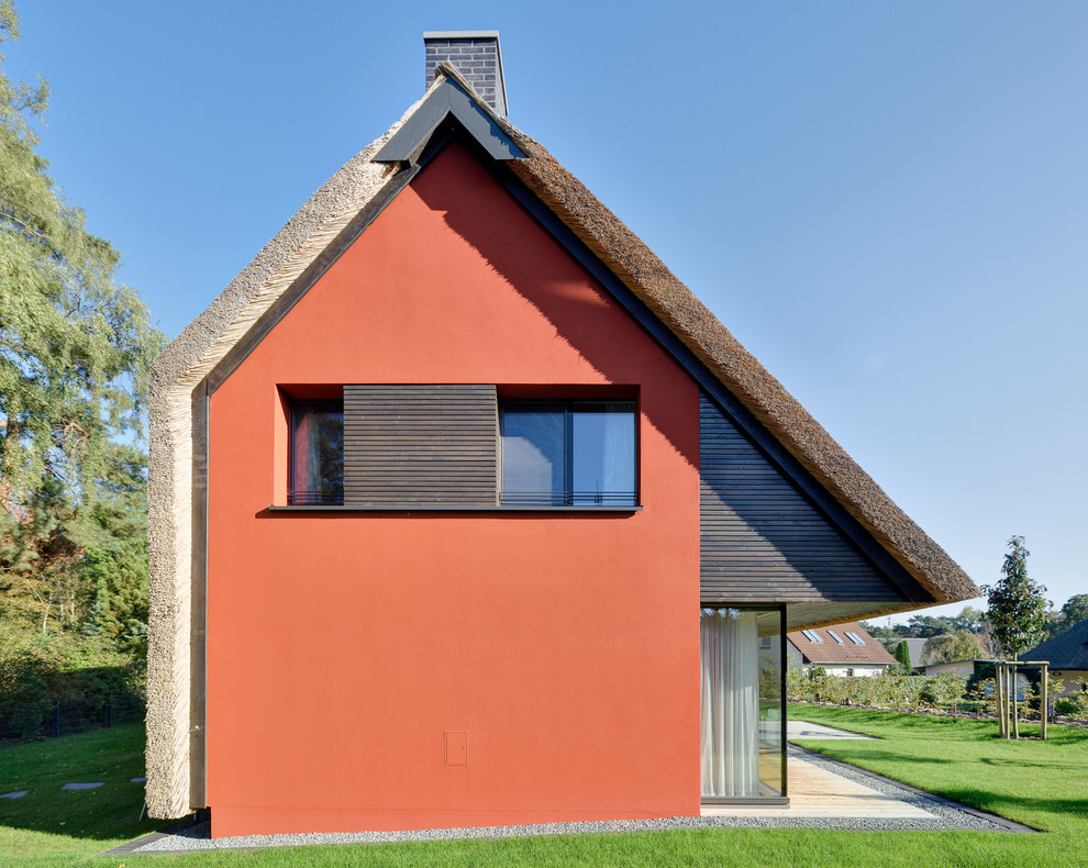 Идея дизайна: красный, маленький, двухэтажный дом в современном стиле с двускатной крышей и комбинированной облицовкой для на участке и в саду