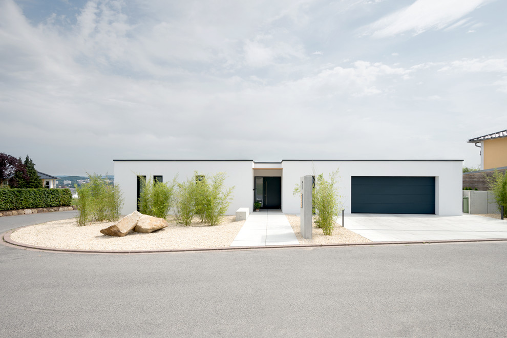 Стильный дизайн: одноэтажный, белый дом среднего размера в стиле модернизм с облицовкой из бетона и плоской крышей - последний тренд