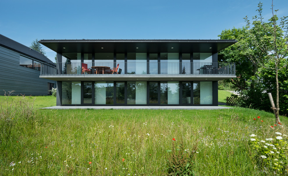 Medium sized modern two floor glass house exterior in Other with a flat roof.