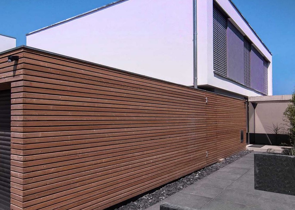 Inspiration for a medium sized and white modern two floor house exterior in Frankfurt with wood cladding.