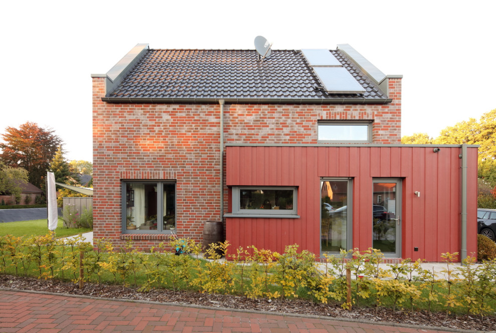 Ejemplo de fachada de casa roja actual de tamaño medio de una planta con revestimientos combinados, tejado a dos aguas y tejado de teja de barro