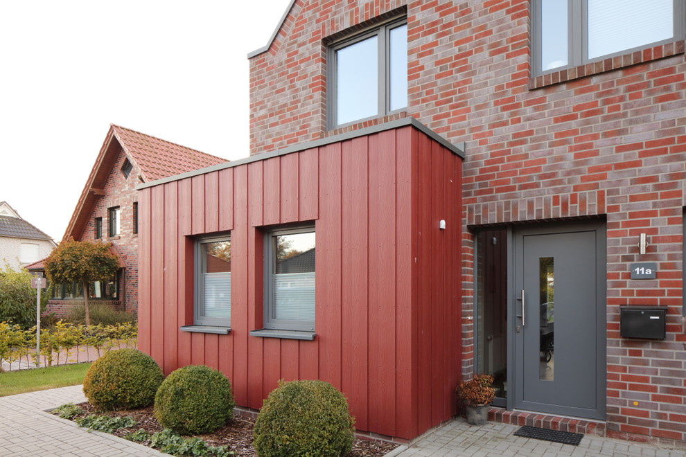 Diseño de fachada de casa roja actual de tamaño medio de una planta con revestimientos combinados, tejado a dos aguas y tejado de teja de barro