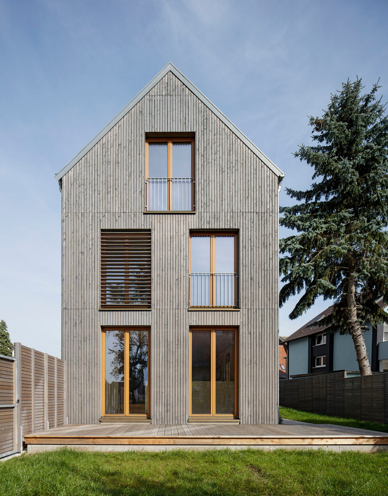 Foto de fachada gris actual de tamaño medio de tres plantas con tejado a dos aguas y revestimiento de madera