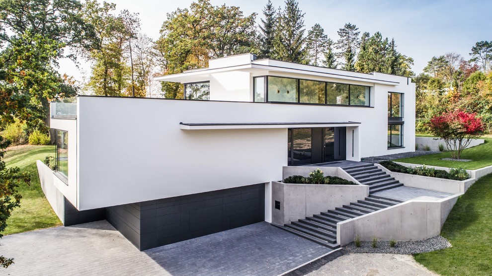 Réalisation d'une grande façade de maison blanche design en stuc à un étage avec un toit plat.