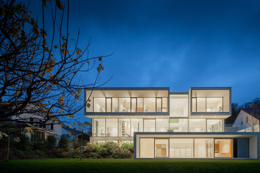 Idee per la facciata di una casa ampia moderna a tre piani con tetto piano e rivestimento in vetro