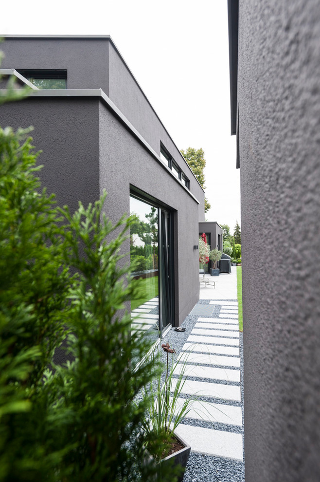 Идея дизайна: большой, двухэтажный, серый частный загородный дом в стиле модернизм с облицовкой из цементной штукатурки, плоской крышей и зеленой крышей