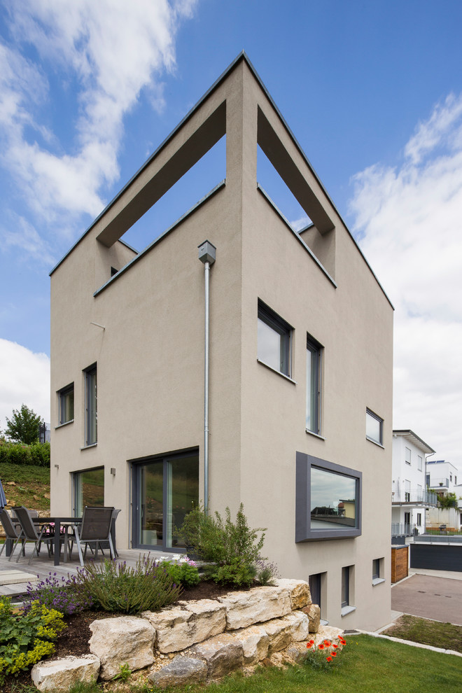 Стильный дизайн: трехэтажный, бежевый частный загородный дом среднего размера в современном стиле с плоской крышей и облицовкой из цементной штукатурки - последний тренд