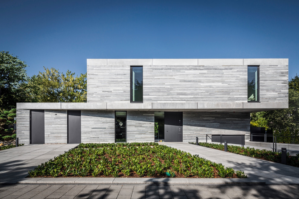 Imagen de fachada gris moderna de tamaño medio de dos plantas con revestimiento de piedra y tejado plano