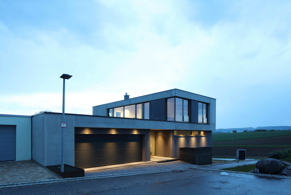 Exemple d'une façade de maison grise tendance en béton à deux étages et plus avec un toit plat et un toit végétal.